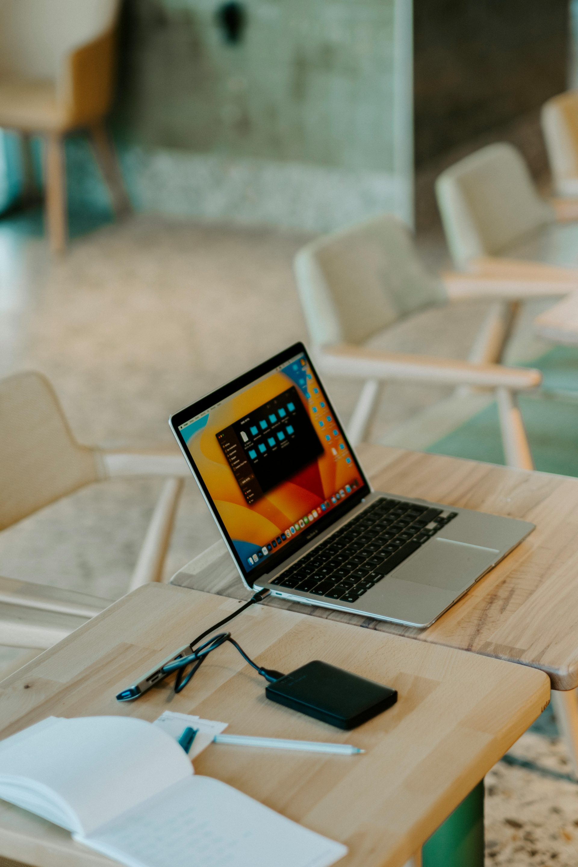 A sleek laptop with accessories on a wooden table in a stylish office setting.